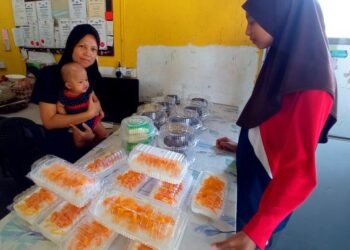 NORLINA Saparon mendukung Nur Nafisa Raihana Jalaludin mempamerkan kek diusahakan di rumahnya untuk dijual di Felda Simpang Waha, Kota Tinggi, Johor. – FOTO/MASTURAH SURADI