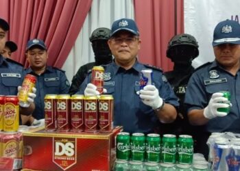 MISBAHUDIN Parmin (tengah) menunjukkan minuman keras yang dirampas dalam serbuan ke sebuah rumah teres di Desa Cemerlang, Ulu Tiram, Johor Bahru.