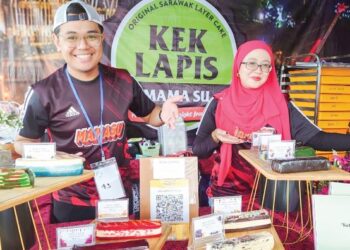 ADZRILL Armani (kiri) menunjukkan antara perisa kek lapis Sarawak yang dijual di gerainya sempena FMJ 2022 di Puteri Harbour, Iskandar Puteri, Johor.