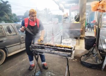 Mohd. Lokman menyediakan sate untuk dibakar bagi tempahan pelanggan di gerainya di hadapan sebuah restoran di Jalan Kukup, Pontian.