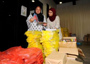 AMIRA Aisya Abdul Aziz (kiri) bersama pembantunya melihat buku-buku yang akan diberikan kepada murid-murid di pejabatnya di Pusat Khidmat Puteri Wangsa Eco Cascadia, JOhor Bahru disini.-UTUSAN/RAJA JAAFAR ALI