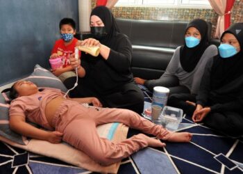 NOOR Suraya Saidin memberi minum susu melalui tiub ke perut yang ditebuk kepada Noor Qaira di rumahnya di PPR Bandar Uda Utama disini. UTUSAN/RAJA JAAFAR ALI