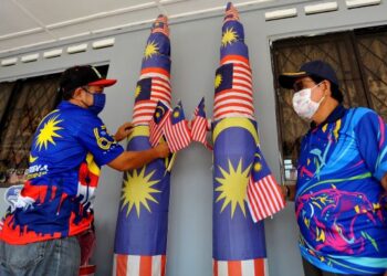 HASSRI Abdul Kadir (kiri) menghiasi  replika bangunan KLCC dengan bendera Jalur Gemilang sambil diperhatikan oleh Mohd Karim Wagiman  bagi sambutan Hari Kebangsaan ke 64 di Kampung Bendahara disini. -UTUSAN/RAJA JAAFAR ALI