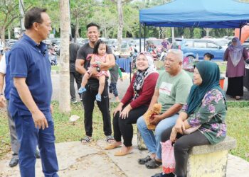 HASNI Mohammad (kiri) beramah mesra dengan pengunjung di Hutan Bandar Simpang Renggam, baru-baru ini.