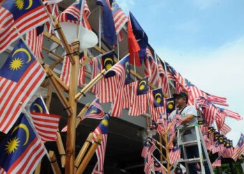 HASSRI ABD. KADIR dengan penuh semangat mengibarkan bendera Jalur Gemilang di halaman rumahnya sebagai persiapan menyambut Hari Kemerdekaan Ke-65 di Kampung Bendahara, Johor Bahru.