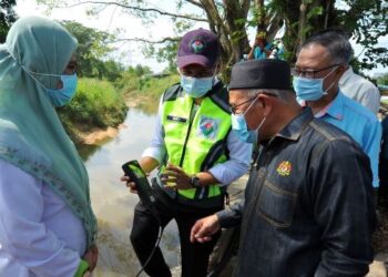 TUAN Ibrahim Tuan Man (kanan) melihat bacaan sampel air Sungai Kim Kim daripada Famey Yusoff di Pasir Gudang, Johor. - UTUSAN/RAJA JAAFAR ALI