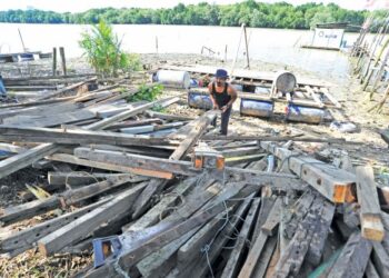FAIZAL Daud memungut dan menyusun kayu-kayu yang hanyut untuk dijadikan perabot di tebing Sungai Tebrau di Johor Bahru, Johor. -UTUSAN/RAJA JAAFAR ALI