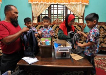 Abdul Razak Abdul Wahab (kiri) bersama isteri Susilawati Saharuddin (dua dari kanan) melayani tiga anak kembarnya Abdul Raqib (dua dari kiri), Abdul Raauf dan Abdul Rafik sebagai persediaan bermulanya sesi persekolahan di rumahnya di Kampung Melayu Raya, Pekan Nanas, Pontian, Johor, semalam. - UTUSAN/RAJA JAAFAR ALI