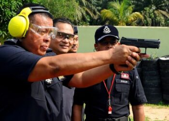 KAMARUL Zaman Mamat melepaskan tembakan sambil diperhatikan Presiden Kelab Gabungan Media Malaysia merangkap Presiden Media Johor, Fauzi Ishak (dua dari kanan)  sempena Pertandingan Menembak Polis Johor Bersama Media Johor di Lapang Sasar Ladang Rem, Kota Tinggi, hari ini. - FOTO/RAJA JAAFAR ALI