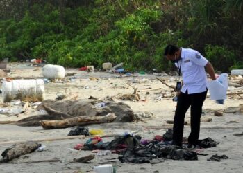 Pegawai dari Kedutaan Indonesia memeriksa barang milik mangsa bot karam di pantai Tanjung Balau, Kota Tinggi.