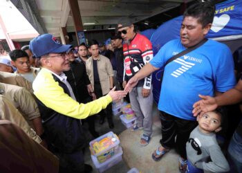 ANWAR Ibrahim menyantuni mangsa banjir ketika melawat PPS SJKC Kampung Tengah, Segamat. - UTUSAN/RAJA JAAFAR ALI