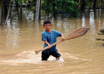 SEORANG kanak-kanak bermain air bersama pendayung di Kampung Pogoh Tengah, Segamat. - UTUSAN/RAJA JAAFAR ALI