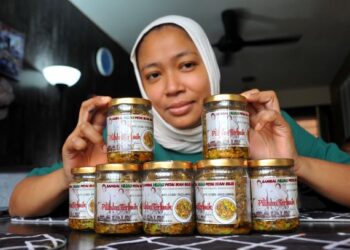 AINIL Noor Qayyum Abdullah menunjukkan sambal hijau petai ikan bilis Warisan Nona Salam yang diusahakan di rumahnya di Kempas, Johor Bahru. – UTUSAN/RAJA JAAFAR ALI
