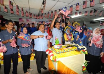 Mohd. Hairi Mad Shah bersama pelajar dan pensyarah mengibarkan bendera Jalur Gemilang selepas memotong kek sempena majlis perasmian Program Ambang Kemerdekaan Peringkat Kolej Kemahiran Johor di Kolej Kemahiran Johor Ungku Mohsin, Johor Bahru disini.-UTUSAN/RAJA JAAFAR ALI
