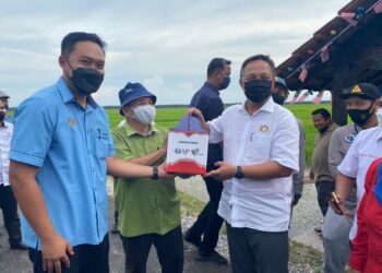HASNI Mohammad (kanan) menerima cenderahati selepas mengadakan lawatan dan walkabout bersama komuniti pesawah padi di Rumah Inap Desa Sungai Balang di Muar, Johor. -UTUSAN/NUR ALINA HASSAN
