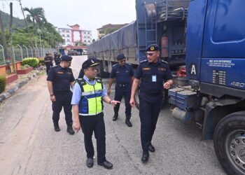 AEDY Fadly Ramli (kiri) melihat sebahagian kenderaan perdagangan yang disita dalam Ops Bersepadu Rentas Sempadan di Kuala Terengganu, hari ini. - UTUSAN/TENGKU DANISH BAHRI TENGKU YUSOFF