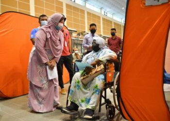 KASEMANI Embong (kiri) beramah mesra dengan penerima vaksin Covid-19 di pusat pemberian vaksin (PPV) di Dewan Majlis Daerah Marang (MDM) di Marang, Terengganu, hari ini. - FOTO/PUQTRA HAIRRY ROSLI