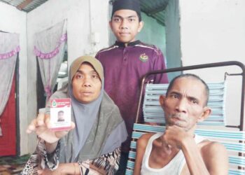 Habibah Awang (kiri) menunjukkan gambar Muhamad Nur yang menghilangkan diri  empat tahun lalu ketika ditemui di Kampung Kuala Samak, Kuala Ketil  semalam.
