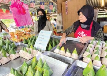 AZIZAN Mat Said (kiri) melihat Fatimah Ayob (kanan) menyusun nasi lemak bungkus daun pisang yang terdiri daripada enam jenis lauk di Kampung Ruat, Yan, Jerai, Kedah. – FOTO/JAMLIAH ABDULLAH