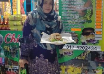 NORLIZA Husain yang bertongkat menyiapkan burger yang ditempah oleh pelanggan di 
kedainya di Kampung Sungai Rotan, Guar Cempedak, Gurun hari ini. -  UTUSAN/OTHMAN YAHAYA