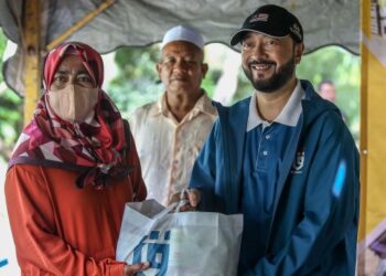 MUKHRIZ Mahathir (kanan) menyampaikan sumbangan kepada salah seorang penduduk ketika hadir ke program ‘Jom Mengemping’ di Kampung Megat Dewa, Jerlun, hari ini. - FOTO/SHAHIR NOORDIN