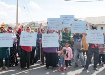 PARA peserta PPR Seri Jerlun memegang sepanduk memohon pihak berwajib membantu menyelesaikan masalah status pemilikan mereka yang belum berpeluang menduduki perumahan itu di Jerlun, Kedah. – FOTO/SHAHIR NOORDIN