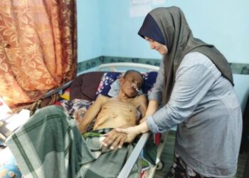 NURUL Atikah Abdullah mengurus suaminya, Zulkifli Mohd. Daud yang terlantar akibat strok  di rumahnya di Kampung Parit Panjang, Baling. – UTUSAN/NORLIA RAMLI