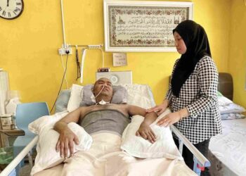 NORUSUHAILI Shamsudin memberi perhatian penuh kepada Masrizal Ishak yang terlantar di rumah mereka di Kampung Masjid Hujung, Hutan Kampung, Alor Setar. – UTUSAN/JAMLIAH ABDULLAH