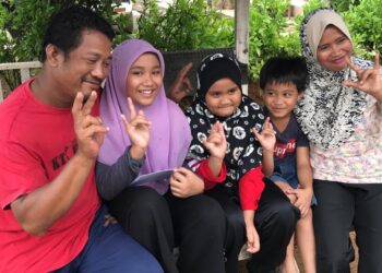 NOR Ain Mohd. Arihan (dua dari kiri) bersama ahli keluarganya menunjukkan simbol bahasa isyarat ‘saya sayang awak’ di rumah mereka di PPMS Kesedar Sejahtera, Gua Musang, Kelantan. - UTUSAN/AIMUNI TUAN LAH