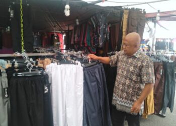 MOHD. SEFFRI Munir sedang menyusun pakaian wanita sambil menunggu pelanggan ke gerainya di tapak ekspo bandar Inderapura di Jerantut, Pahang. - UTUSAN/HARIS FADILAH AHMAD