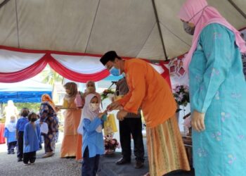 MOHAMAD Yasid Bidin menyampaikan sumbangan hari raya kepada salah seorang kanak-kanak Tabika Kemas sempena Majlis Perasmian Program Qukis dan Promosi Jualan Aidilfitri Kemas Negeri Sembilan di Pusat Kegiatan Masyarakat Kemas, Rembau, Negeri Sembilan, hari ini. - FOTO/NOR AINNA HAMZAH
