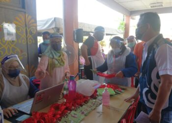 RAZALI Idris (kanan) mendengar taklimat mengenai proses vaksinasi di pusat pemberian vaksin (PPV) Outreach Sekolah Menengah Kebangsaan Bukit Besi di Dungun hari ini. - UTUSAN/NIK NUR IZZATUL HAZWANI NIK ADNAN