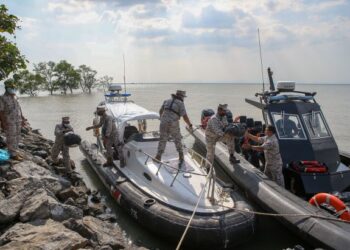 ANGGOTA Maritim Malaysia memindahkan daun ketum ke dalam bot setelah ditinggalkan penyeludup di atas batu di pesisiran laut kawasan Kurung Tengar, Kuala Perlis, semalam.