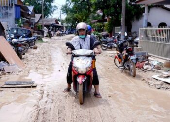 PENDUDUK melalui jalan yang berlumpur akibat kejadian banjir di Kampung Lembah Jaya, Ampang, kelmarin.