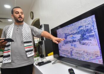 ABDALLAH Ismail menunjukkan perkembangan terkini keadaan di Gaza, Palestin ketika ditemui di rumahnya di Kampung PCB, Kota Bharu, Kelantan. - UTUSAN/YATIMIN ABDULLAH