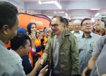 ANWAR Ibrahim (tengah) beramah mesra dengan petugas-petugas barisan hadapan semasa lawatan rasminya ke PPS SMK Tengku Panglima Raja, Pasir Mas, Kelantan, hari ini. - FOTO/MUSTAQIM MOHAMED