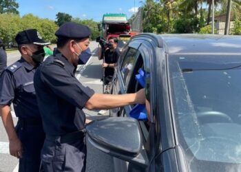 MUHAMAD Zaki Harun menyampaikan bungkusan makanan dan risalah keselamatan jalan raya sempena pelancaran Op Selamat Ke-18 di laluan masuk ke Pasir Puteh, Kelantan, hari ini. - FOTO/TOREK SULONG
