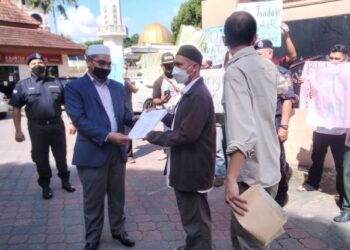 MOHD. Asri Mat Daud menerima memorandum daripada wakil penduduk, Ali Hanafiah Mohamed di depan Kompleks Kota Darulnaim, Kota Bharu, Kelantan, hari ini. - FOTO/ROHANA MOHD. NAWI