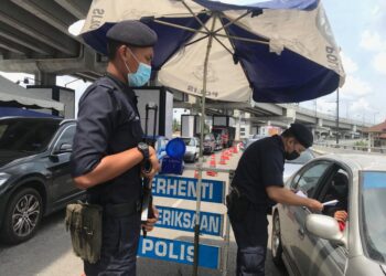 SEORANG daripada rakan sepasukan Khalid Yusoff memeriksa dokumen rentas daerah dikemukakan pemandu di SJR Jalan Hamzah, Kota Bharu, Kelantan. - MINGGUAN/ROHANA MOHD. NAWI