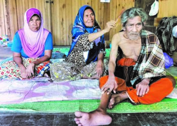 SITI Fatimah Awang Ngah menyikat rambut abangnya, Arul Awang Ngah sambil diperhatikan anak saudaranya, Zaharah (kiri) di kediaman mereka di Kampung Tembusu, Limbat, Kota Bharu, Kelantan.