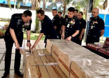 MUHAMAD Zaki Harun (kiri) melihat rokok seludup yang dirampas semasa sidang media di IPK,Kota Bharu, Kelantan, hari ini. - FOTO/ROSLIZA MOHAMED