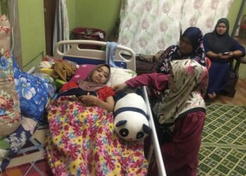 CHE Norhayati Mohamed (kanan) sedang melihat keadaan Anies Karmila yang terlantar akibat kemalangan jalan raya bulan lalu di rumahnya di Kampung Limau Nipis, Bukit Bakar, Machang,Kelantan. UTUSAN/ROSMIZAN RESDI