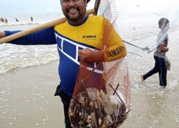ZAHARI Che Ali menggunakan sauk besar untuk menangkap kerang kampak di Pantai Baru, Bachok, semalam. – UTUSAN/TOREK SULONG