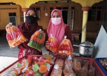 MASTURA Mohd. Lazim (kiri) bersama ibunya, Rohimah Teh menunjukkan kerepek ginang yang siap dibungkus sebelum dipasarkan kepada pelanggan. – UTUSAN/ROHANA MOHD. NAWI