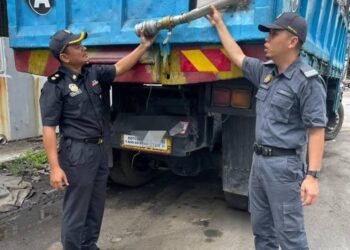 ANGGOTA penguat kuasa KPDN Perak menunjukkan lori yang disita dalam serbuan di kawasan Perindustrian Anson di Teluk Intan semalam. - UTUSAN/IHSAN KPDN PERAK