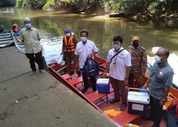ABDUL RAHMAN Mohamad (depan, dua dari kiri) bersama kakitangan Jabatan Kesihatan Lipis dan
petugas barisan hadapan menaiki bot untuk melaksanakan program vaksinasi di Kampung Kuala
Kenong, di Lipis, Pahang. -  UTUSAN/HARIS FADILAH AHMAD