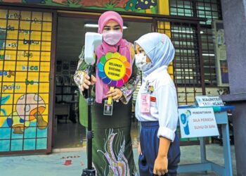 SEORANG guru memeriksa suhu seorang murid prasekolah sebelum memasuki bilik darjah bagi sesi persekolahan bersemuka di Sekolah Kebangsaan Seksyen 7 Bandar Baru Bangi, semalam. – GAMBAR/FARIZ RUSADIO