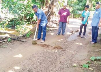 MOHAMAD Ibrahim (kiri) membuat laluan untuk memudahkan air hujan mengalir ke lubang khas di belakang rumahnya bagi mengelak banjir kilat di Kampung Batu 2, Jalan Jeniang-Gurun di Gurun, Kedah. -UTUSAN/OTHMAN YAHAYA