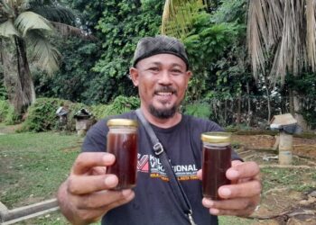 ADI MOHD. YASIN  menunjukkan produk madu kelulut yang dibotolkan untuk dijual kepada pelanggannya.