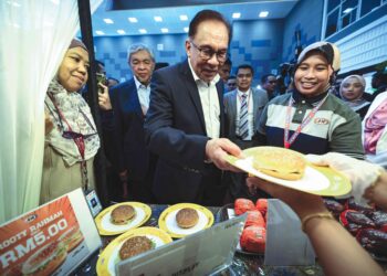 Anwar Ibrahim mencuba juadah yang disediakan pada Kenduri Menu Rahmah Kasih Sayang di Parlimen, semalam. – JABATAN PENERANGAN